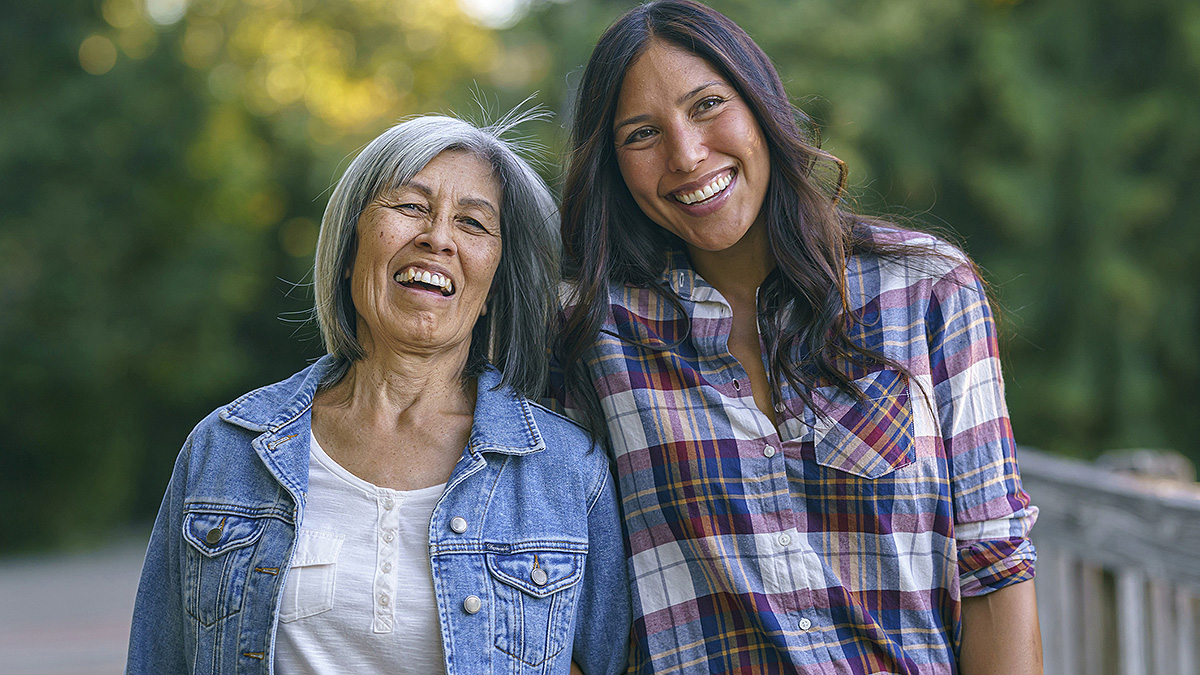 Mother and daughter smiling outdoors.