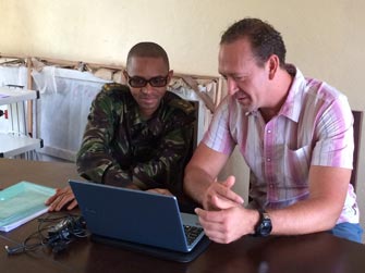 Greg (a la derecha), detective de enfermedades de los CDC, habla sobre el rastreo de contactos de la enfermedad del Ébola con un oficial de las Fuerzas Armadas de Sierra Leona.