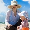 Foto de una madre y su bebé con sombreros y gafas de sol.