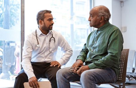 Un doctor hablando con un paciente mayor.