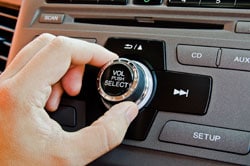Mano girando el botón del volumen en un radio de un carro