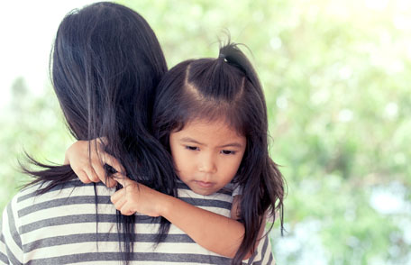 Una madre sostiene en sus brazos a su hija pequeña.