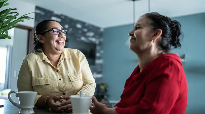 Dos mujeres latinas hablando y sonriendo.