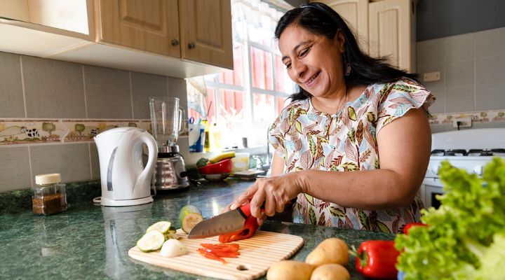 Una mujer cortando vegetales en la cocina