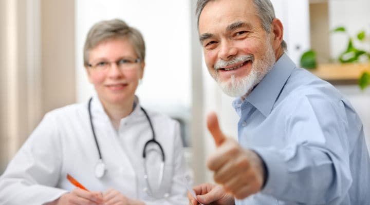 Un paciente junto con su médico, sonriendo con su pulgar arriba
