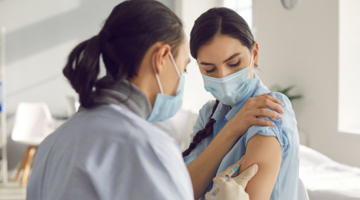 Profesional de la salud aplicando una vacuna en el brazo de una mujer
