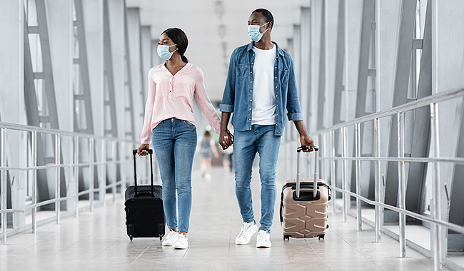 Viajes internacionales Una pareja caminando en el aeropuerto y con mascarillas.