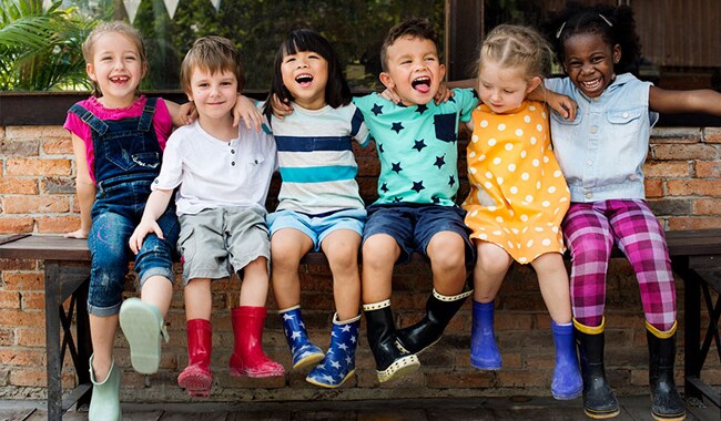 Un grupo de niños sentados en un banco y sonriendo