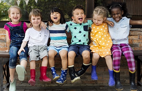 Varios niños sonrientes sentados juntos en un banco.