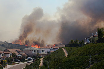 Un incendio forestal cercano a unas casas Un incendio forestal cercano a unas casas