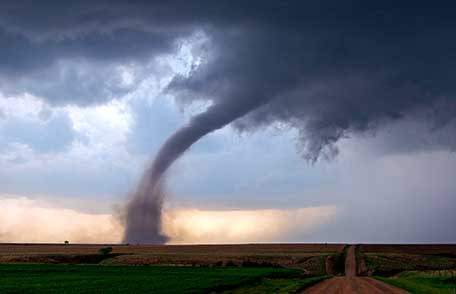 El embudo de un tornado toca el suelo en un campo rural levantando escombros. El embudo de un tornado toca el suelo en un campo rural levantando escombros.