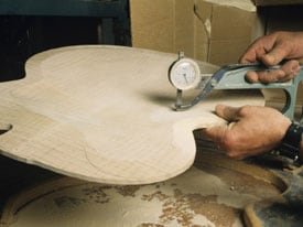 Manos que miden con calibers la espesura de una guitarra hecha a mano 
