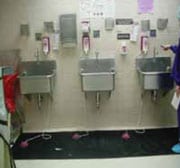 Estaciones para lavarse las manos con fregaderos, dispensadores de jabón en la pa-red y tapetes sobre el piso