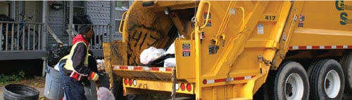 2. Trabajador de recolección de desechos sólidos que carga contenedores en un vehículo de recolección de desechos
