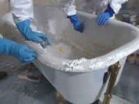 Trabajadores removiendo la pintura de una bañera.