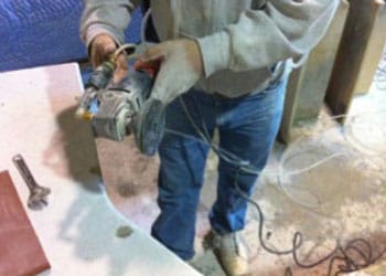 Un trabajador usa una amoladora angular con un disco de pulido para hacer el acabado de un mesón de piedra. La herramienta con toma de agua ayuda a reducir la exposición al polvo de sílice cristalina respirable que se genera durante las operaciones de amolado y pulido. 