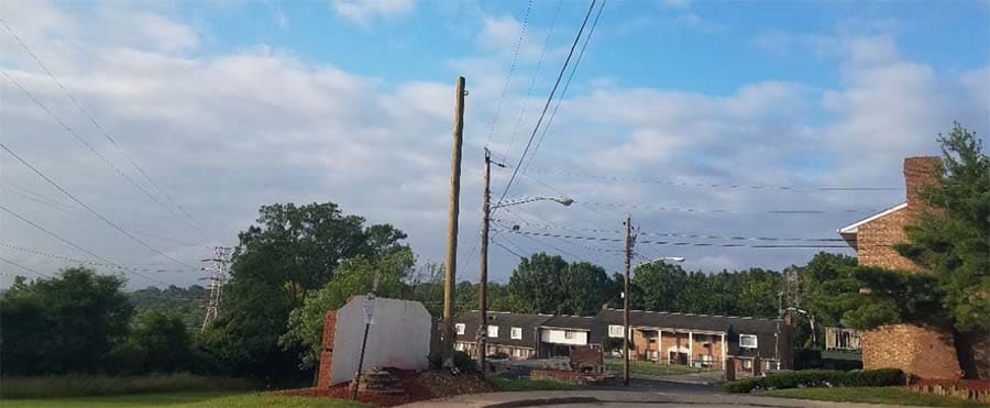 foto de la calle sin salida con un poste nuevo, un cartel de conjunto residencial y cables eléctricos arriba