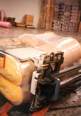 Foto 2. Esta foto ilustra la abrazadera conectada al mástil del montacargas que se usa para agarrar y sostener en su lugar a los rollos de fibra de vidrio.
