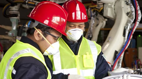 trabajadores de fábrica con cascos y respiradores