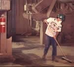 Trabajador barriendo pisos en una planta de fabricación de láminas de fibra.