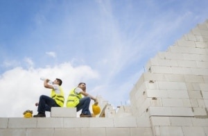 Dos trabajadores de la construcción sentados durante un descanso y bebiendo agua 