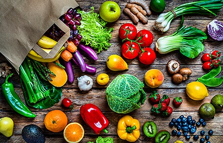 Una bolsa de papel con una variedad de frutas y verduras
