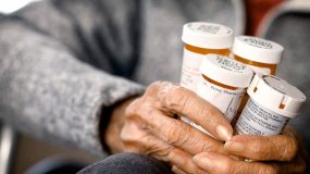 Older adult woman holding several prescription medicine bottles