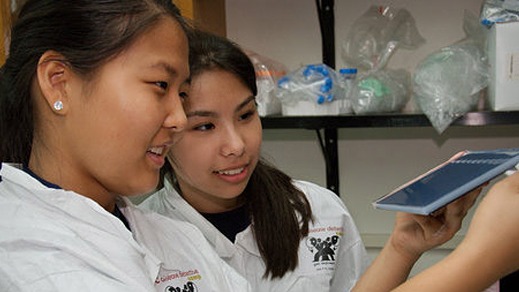 two young, asian women looking at a medical device