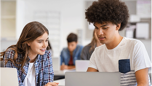 a girl and boy staring at a laptop