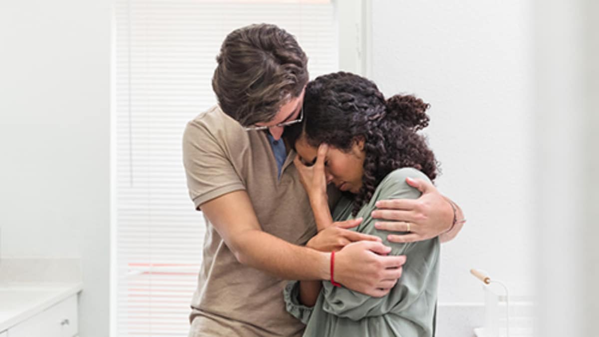 Young man hugs crying young woman