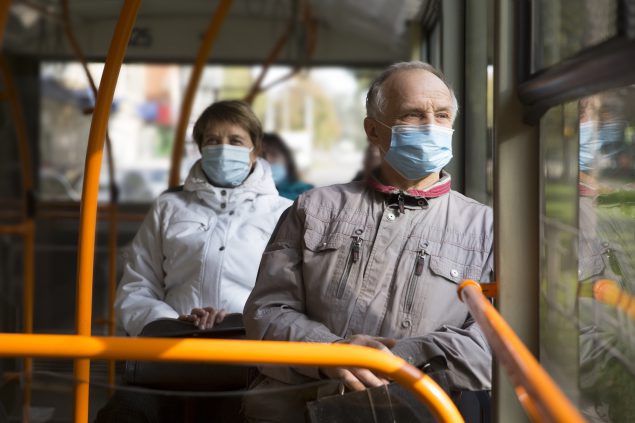 Senior man wearing medical face mask sitting in the bus 