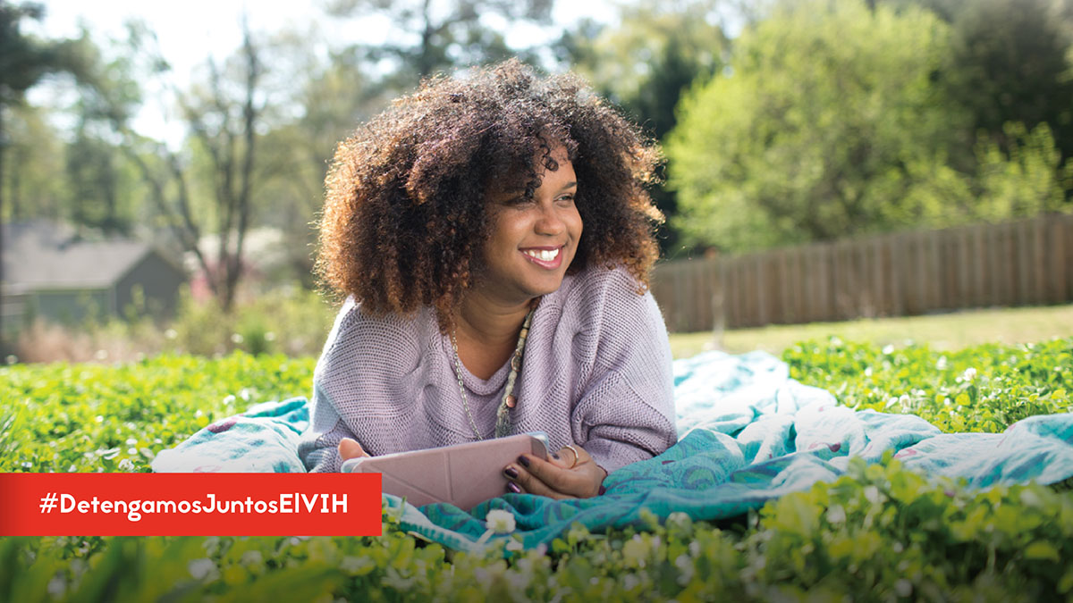 TwitterPosts-STSH-HTW-2020 ¿Sabías que el tratamiento del #VIH reduce la cantidad de virus que hay en tu cuerpo? Puedes mantenerte saludable durante muchos años y prevenir la transmisión del VIH a otros. Aprende más: https://bit.ly/2MtrSLS #DetengamosJuntosElVIH - Woman laying out side on blanket smiling reading while holding a tablet