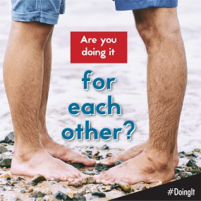Image displays the lower legs of two men facing each other while standing barefoot on a rocky beach, along with the following text:  Are you doing it for each other?