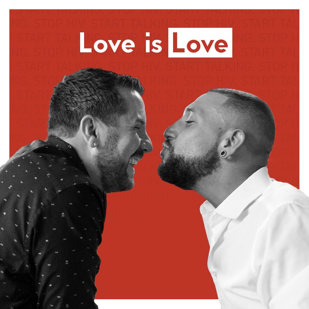 Two men sharing a kiss with the words love is love written in the background.