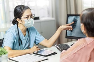 Healthcare worker with patient pointing at x-ray image