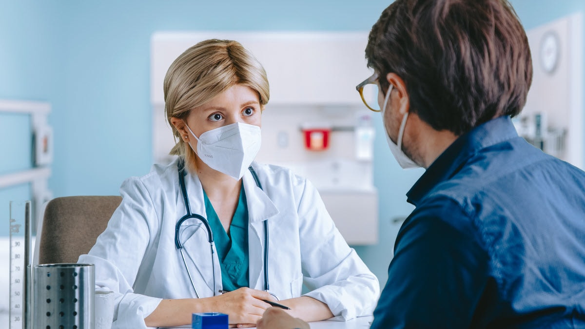 Female doctor talking to male patient both wearing N95 masks