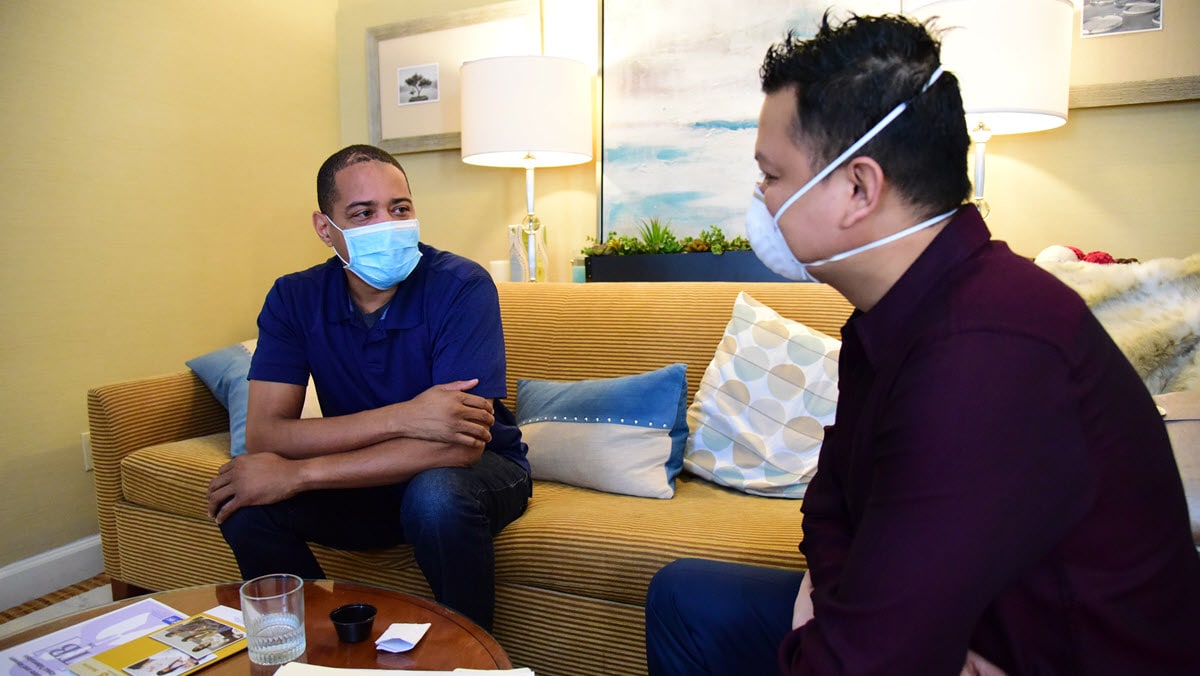 A person with TB disease wearing a mask meets with a masked health care worker to receive TB treatment.