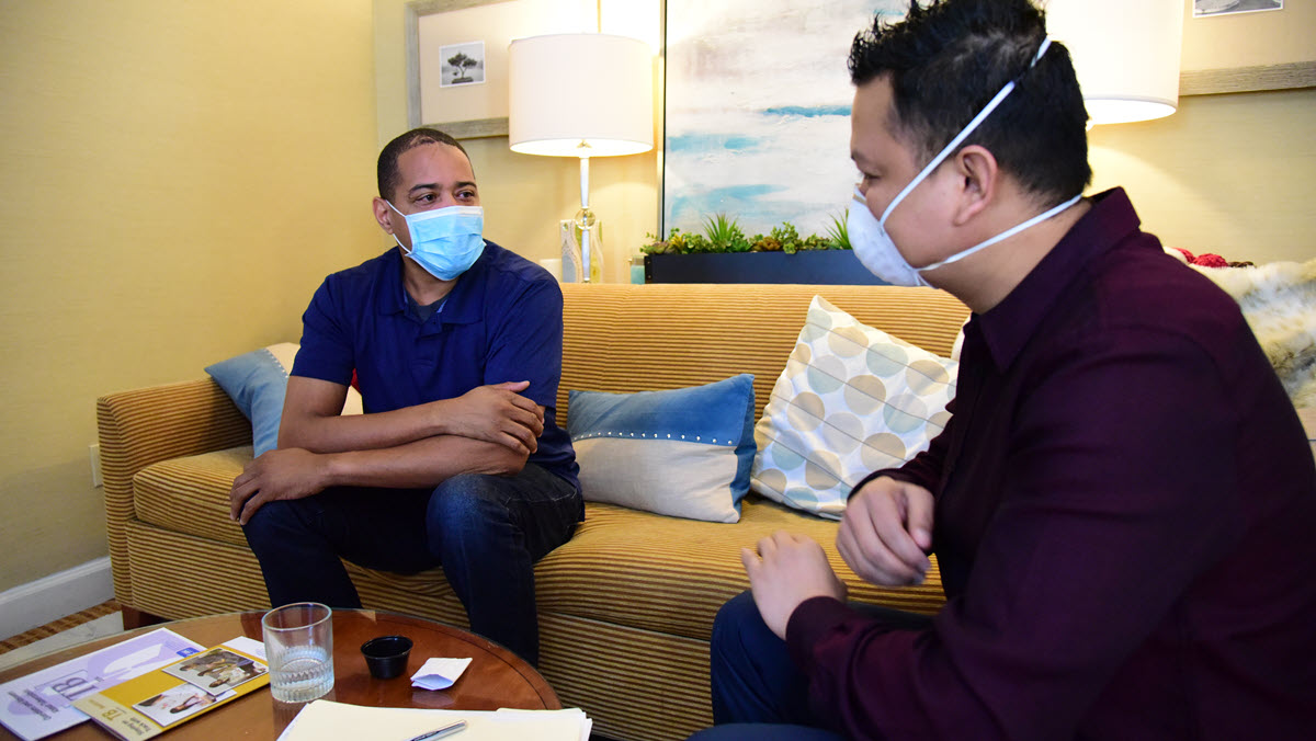 A health care worker wearing a N95 respirator provides treatment for a patient wearing a mask.