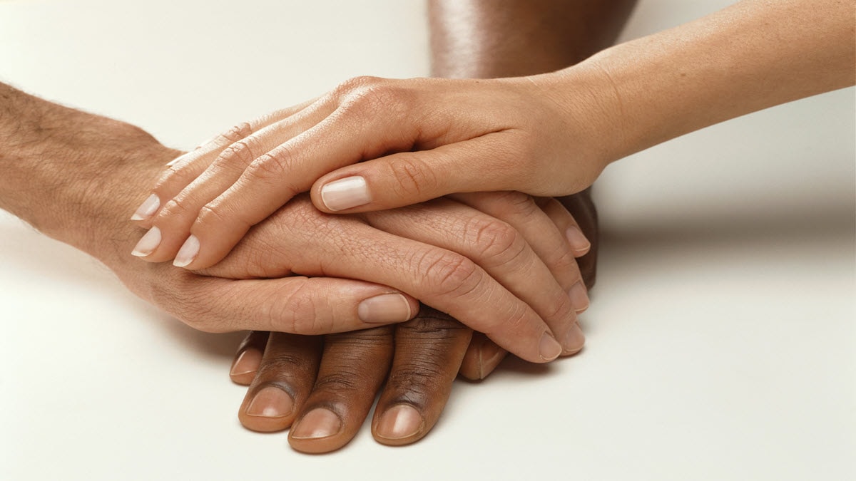 Three multiracial hands stacked on top of each other