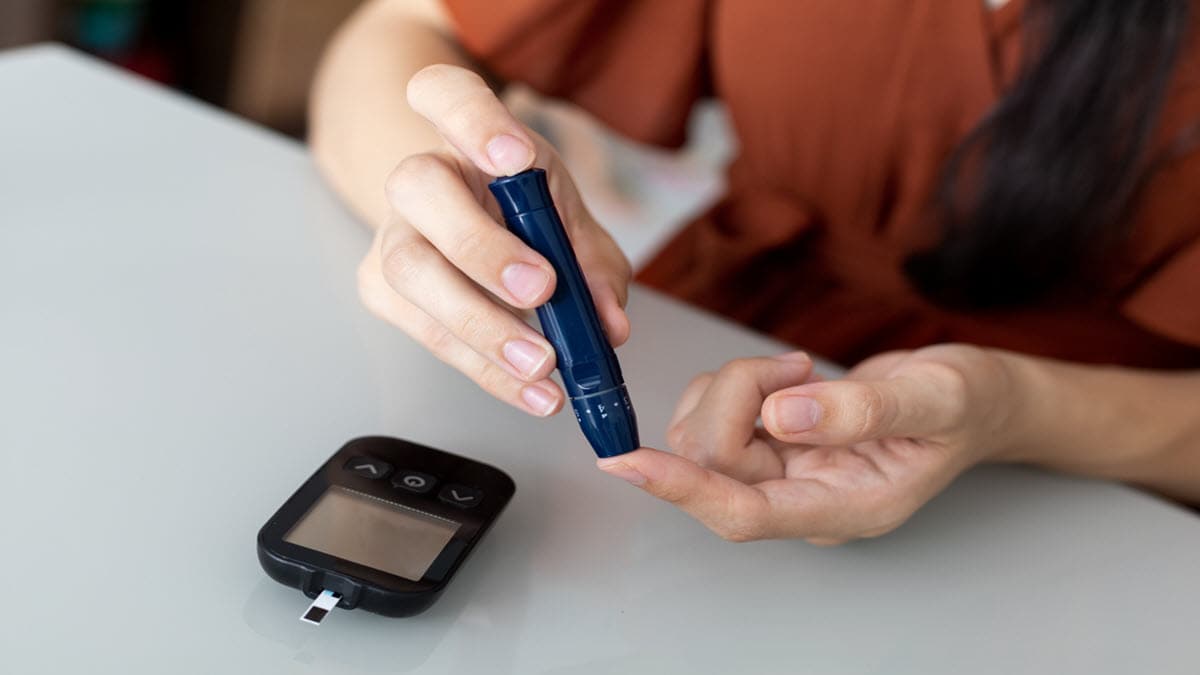A person with diabetes performs blood sugar level check by doing a finger-prick test.
