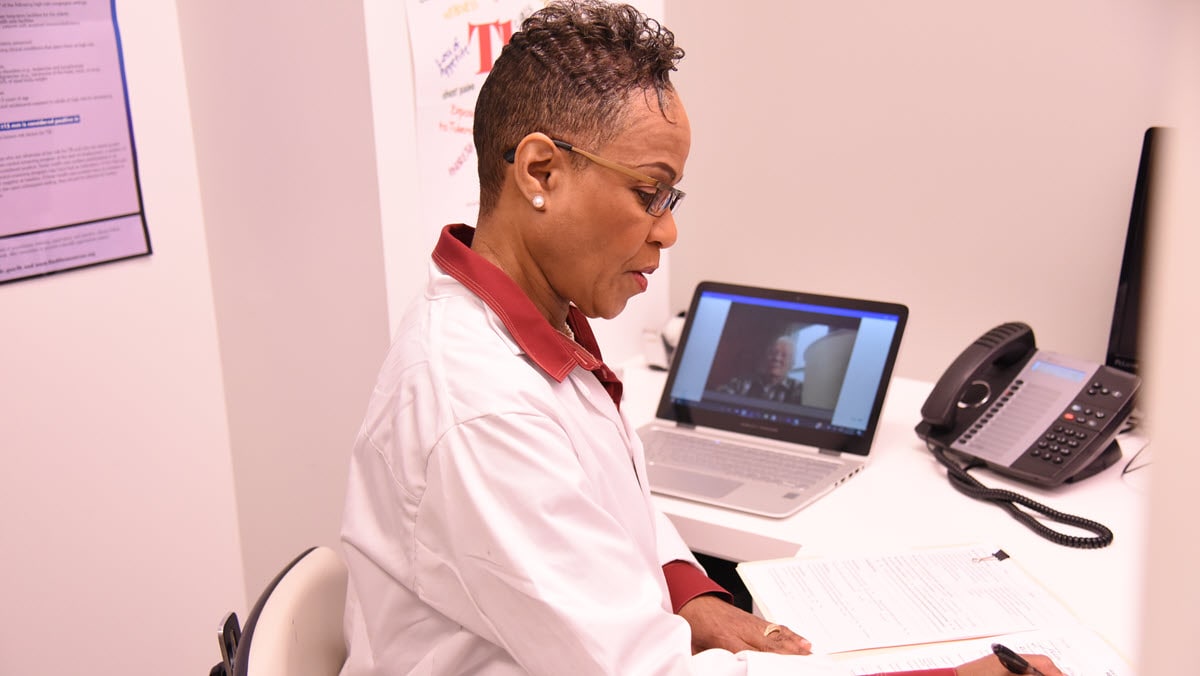 A health care provider watches a patient take TB medicine on a computer