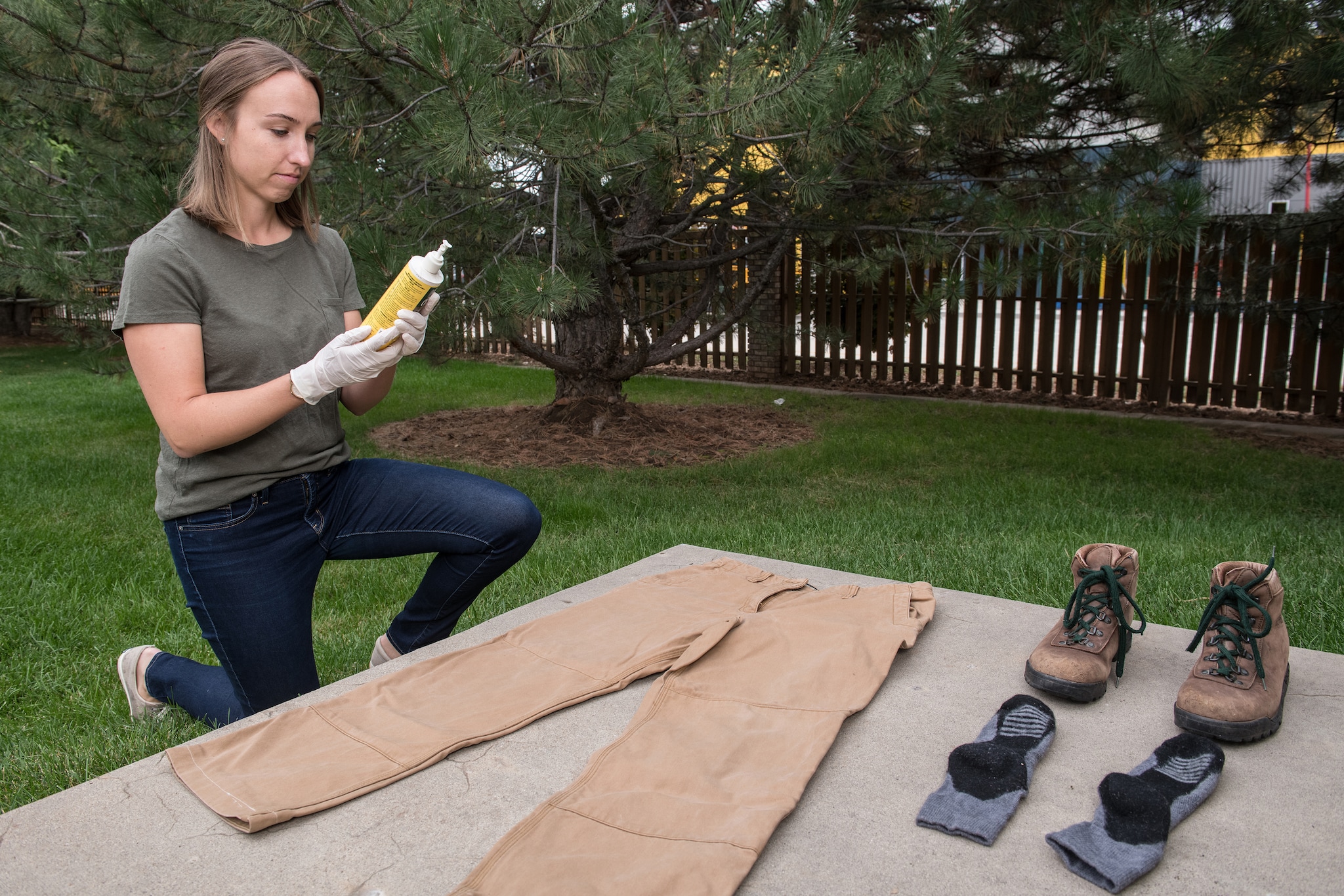 Photo of a woman reading the instructions on a permethrin bottle in order to correctly apply it to her clothing.