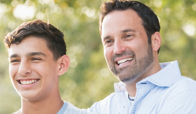 Father and teenage son both smiling