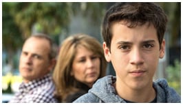 Adolescente masculino con padres en el fondo