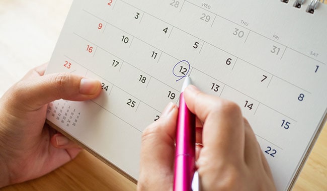 Woman circling a date on her calendar.