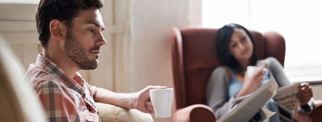 Un hombre y una mujer mirando el periódico con una taza de café en la mano
