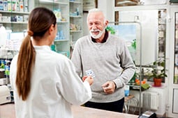 Smiling man receiving medication from his pharmacist.