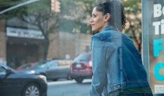 Mujer sentada mirando hacia la calle en una ciudad