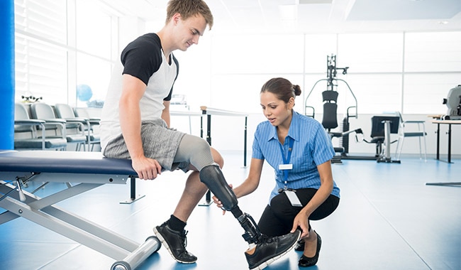 Physical therapist helping a patient put on his prosthetic leg.