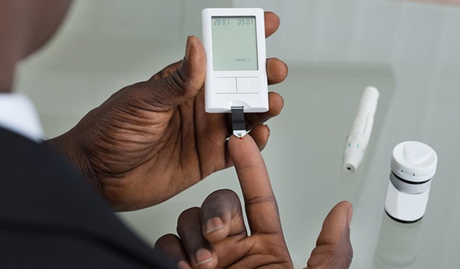 Man checking his blood glucose level with a meter.